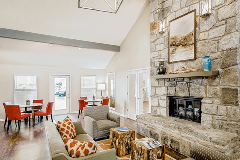 a living room with a stone fireplace and a table with chairs